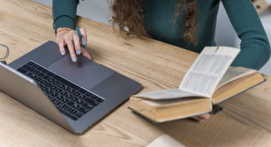 close-up-student-working-with-laptop-dictionary